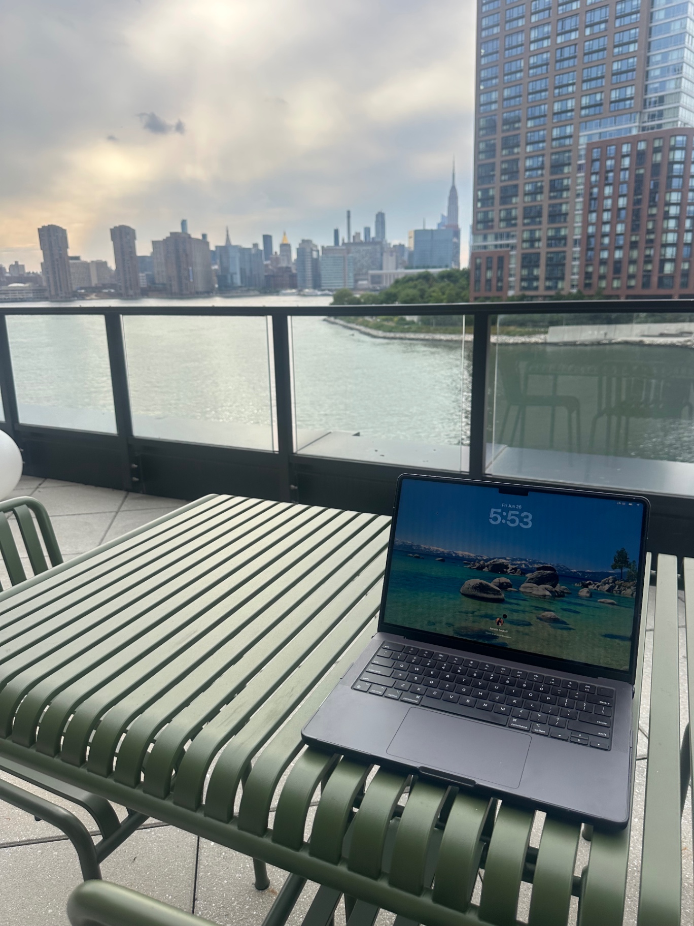 Open laptop on a terrace work table with the NYC skyline behind it